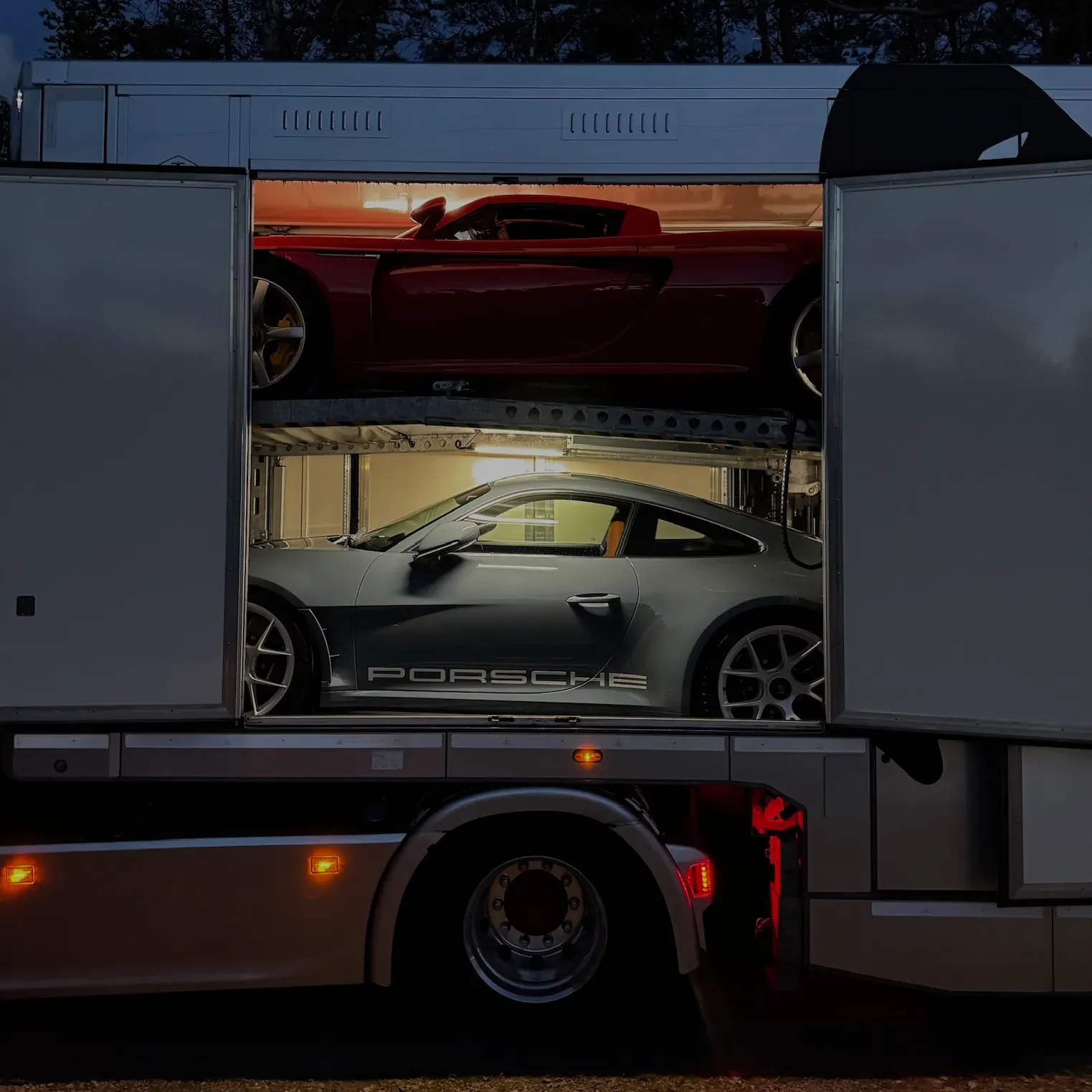 Two Porsches on both decks of the covered trailer
