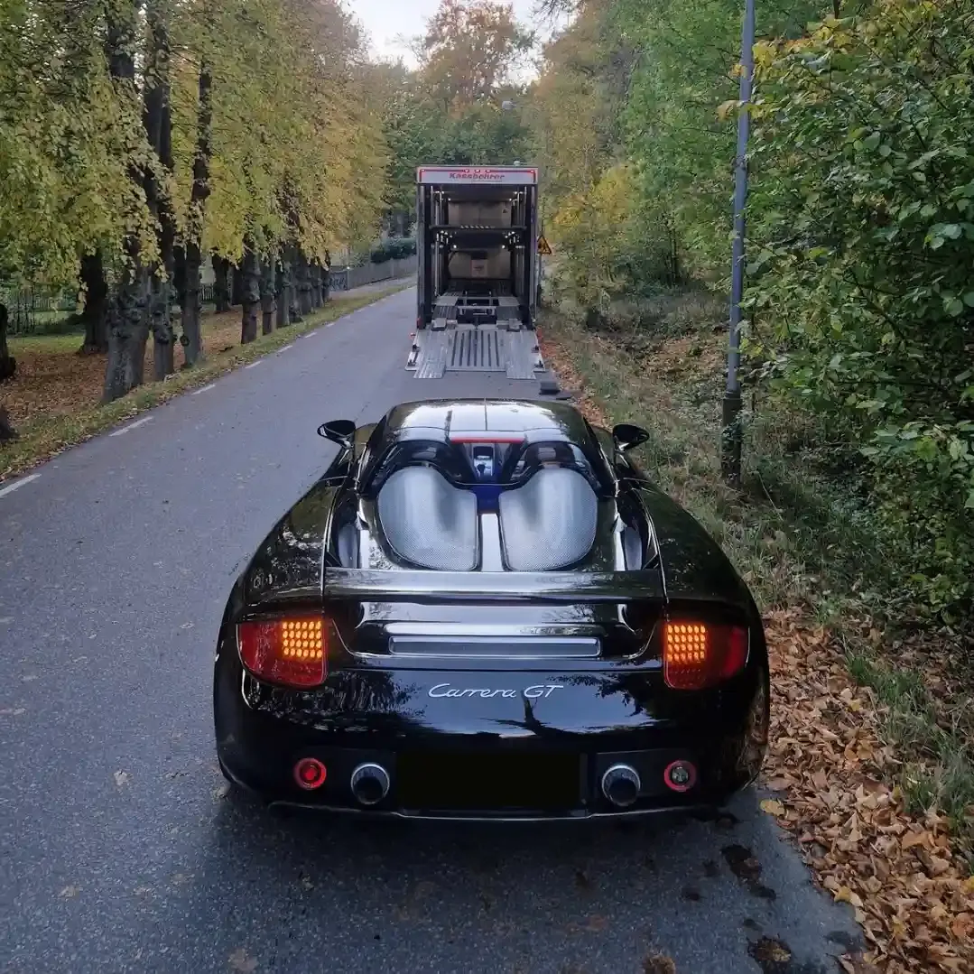 A Porsche Carrera GT in front of a covered transport trailer