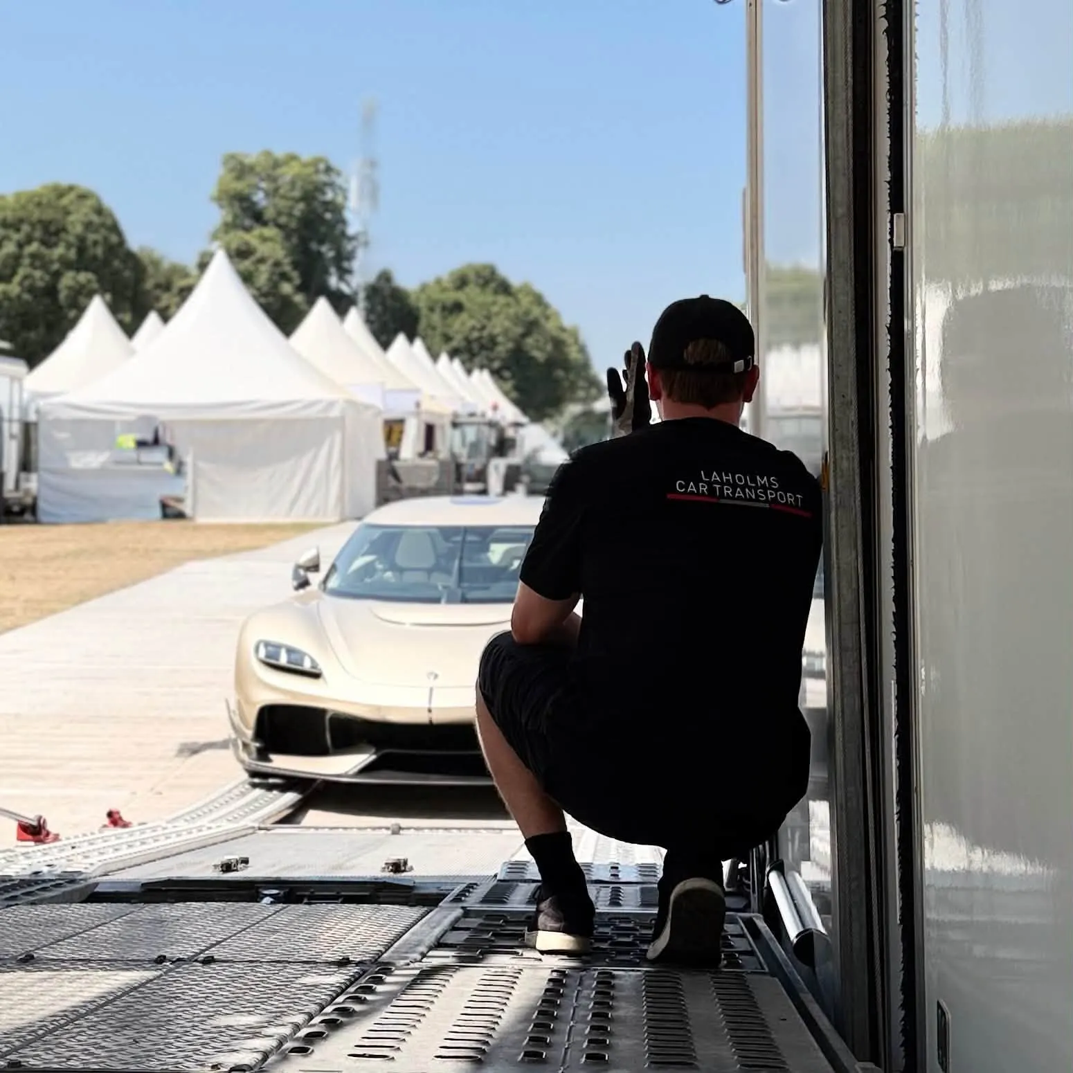 A Laholms Biltransport driver guides a hypercar out of the covered trailer at an event